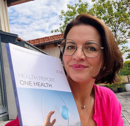 Foto von Rebekka Thor mit dem Buch Health Report 2026 draußen als Portrait
